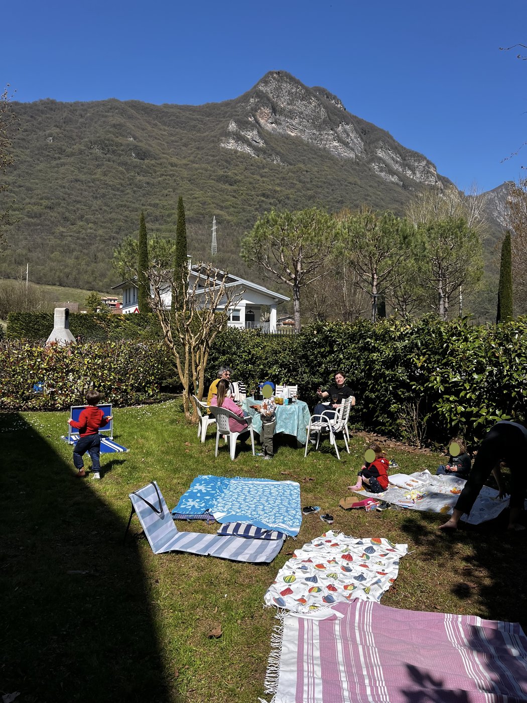 Der Hausgarten mit Picknickdecken auf dem Rasen und den Bergen im Hintergrund